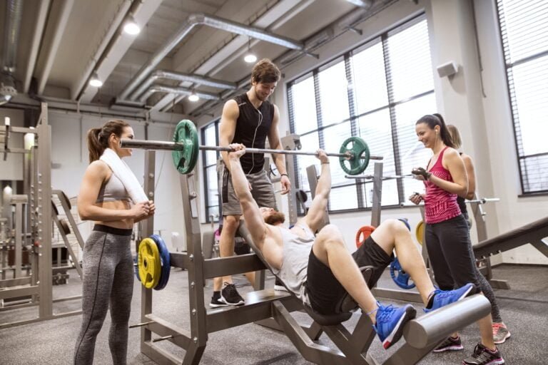 Grupo de personas en el gimnasio entrenando levantamiento de pesas