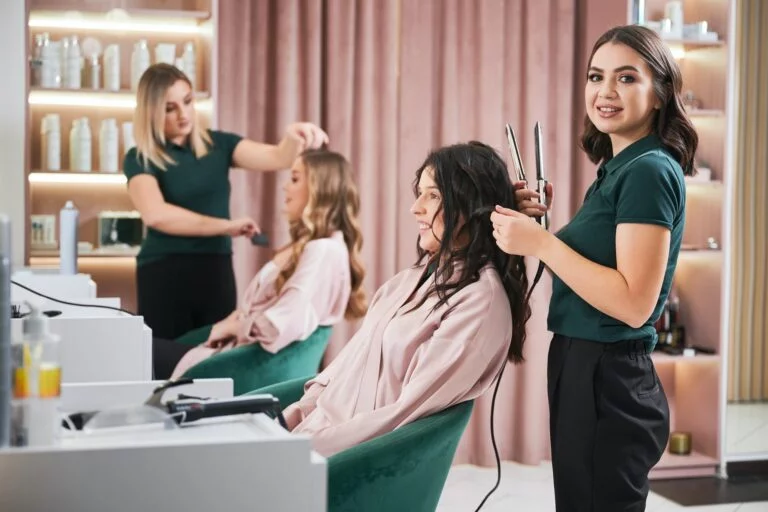 Estilista rizando el cabello de mujer en salón de belleza.