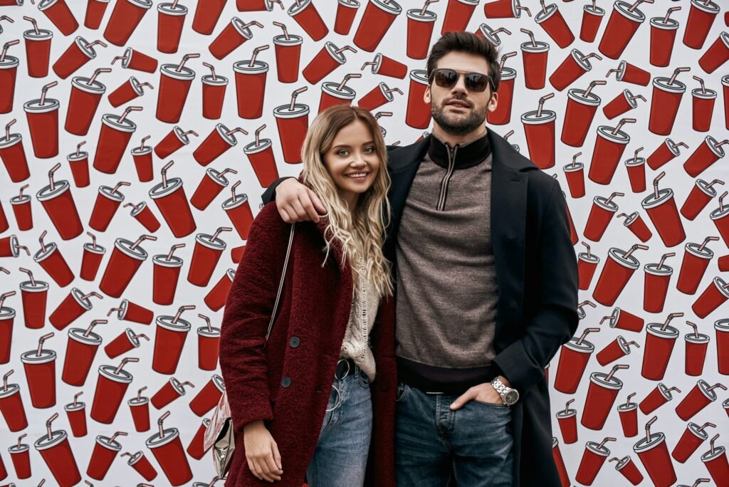 Young couple at the street brand wall background. Brand wall designed with cups