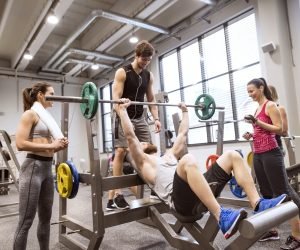 Grupo de personas en el gimnasio entrenando levantamiento de pesas